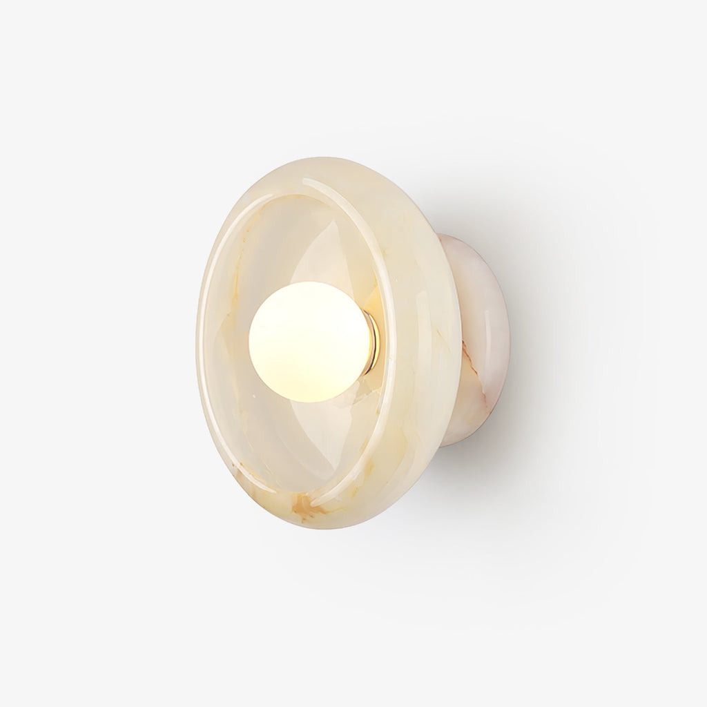 A round jade-toned disc wall sconce glows softly around its centred bulb, mounted flush on a plain studio wall for this Clérachic bedroom light.