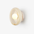A round jade-toned disc wall sconce glows softly around its centred bulb, mounted flush on a plain studio wall for this Clérachic bedroom light.