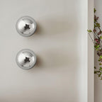 Polished sphere wall sconce with warm reflected glow