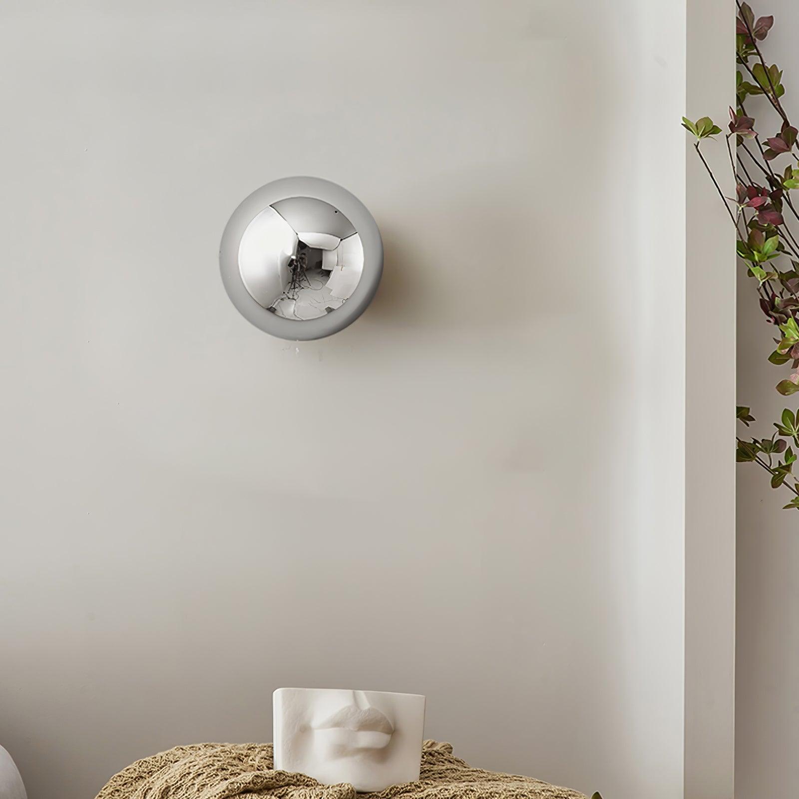Polished sphere wall sconce in black with warm glow