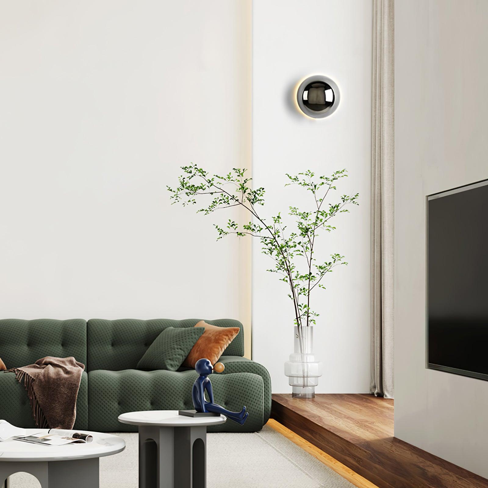 Polished sphere wall sconce glowing in a styled space