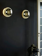 Polished sphere wall sconce with reflective finish on a wall
