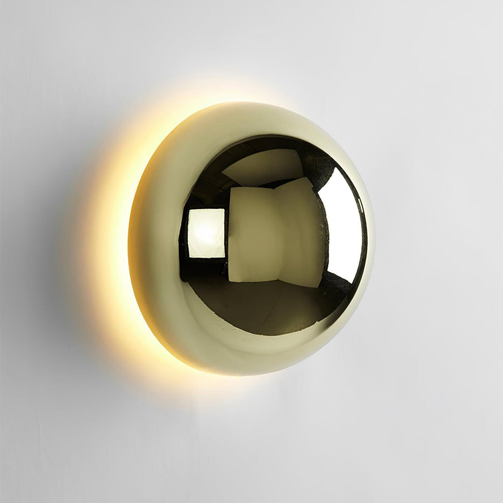 Polished sphere wall sconce in gold reflecting its surroundings