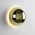 Polished sphere wall sconce in gold reflecting its surroundings