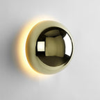 Polished sphere wall sconce in gold reflecting its surroundings