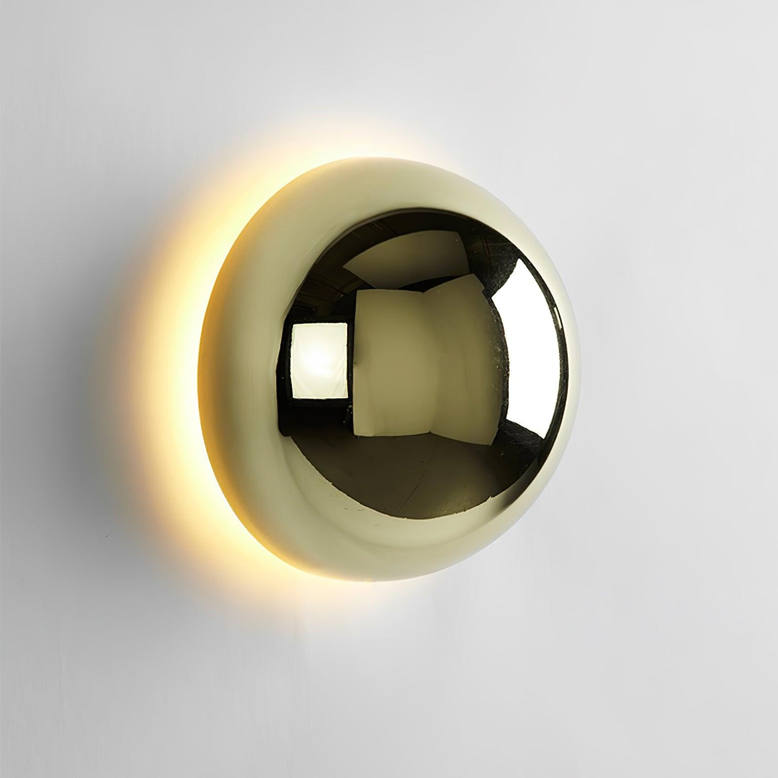 Polished sphere wall sconce in gold reflecting its surroundings