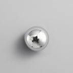 Polished sphere wall sconce lit against a dark wall