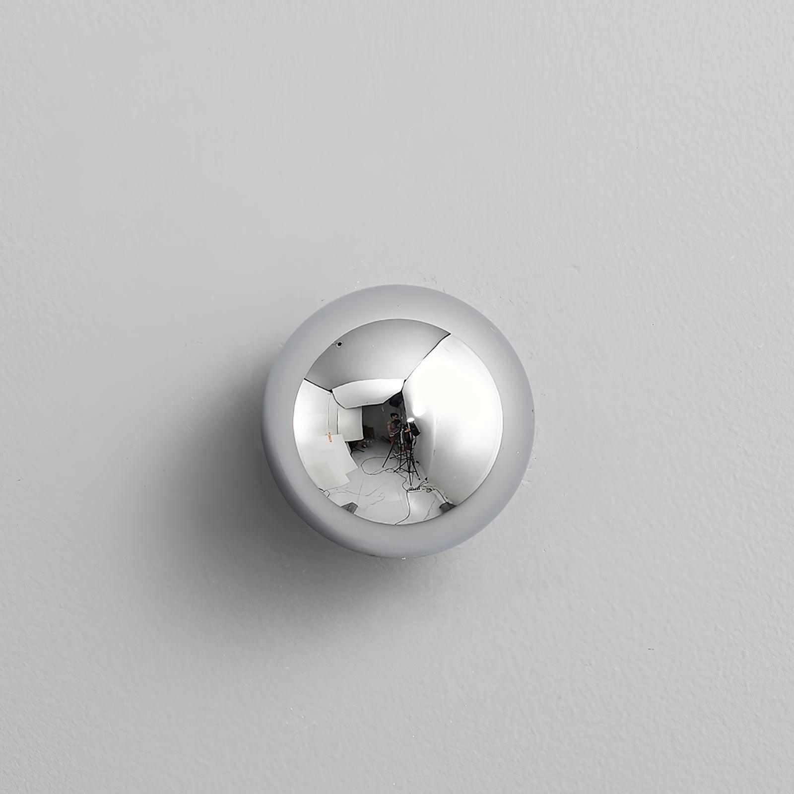 Polished sphere wall sconce lit against a dark wall