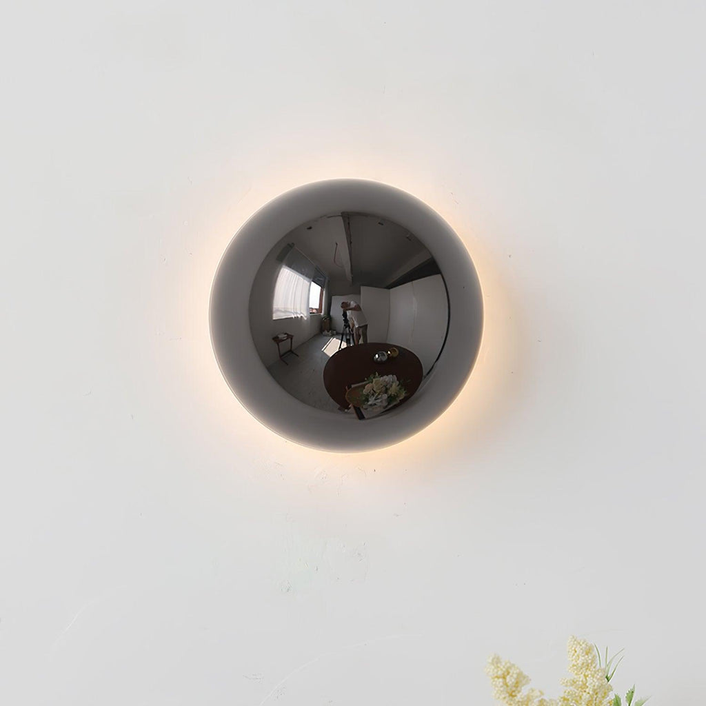 Polished sphere wall sconce reflecting light on a wall