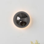 Polished sphere wall sconce reflecting light on a wall