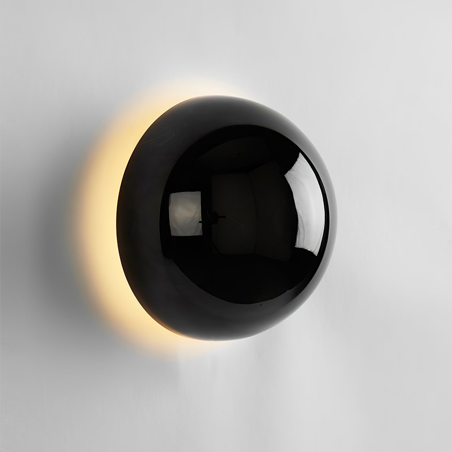 Polished sphere wall sconce glowing softly on a wall