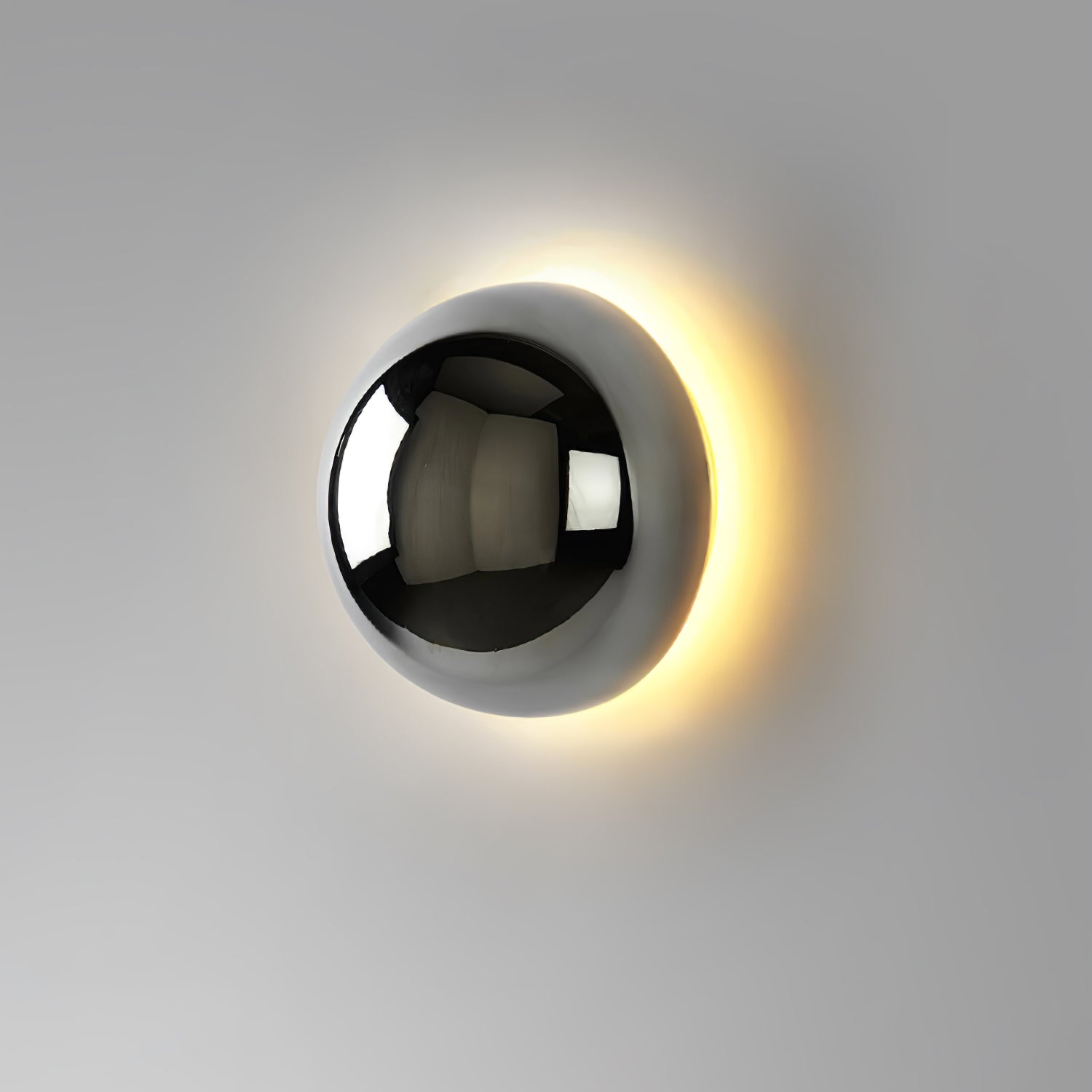 Polished sphere wall sconce lit warmly against a wall