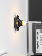 Eclipta wall sconce glowing beside a piece of wall art