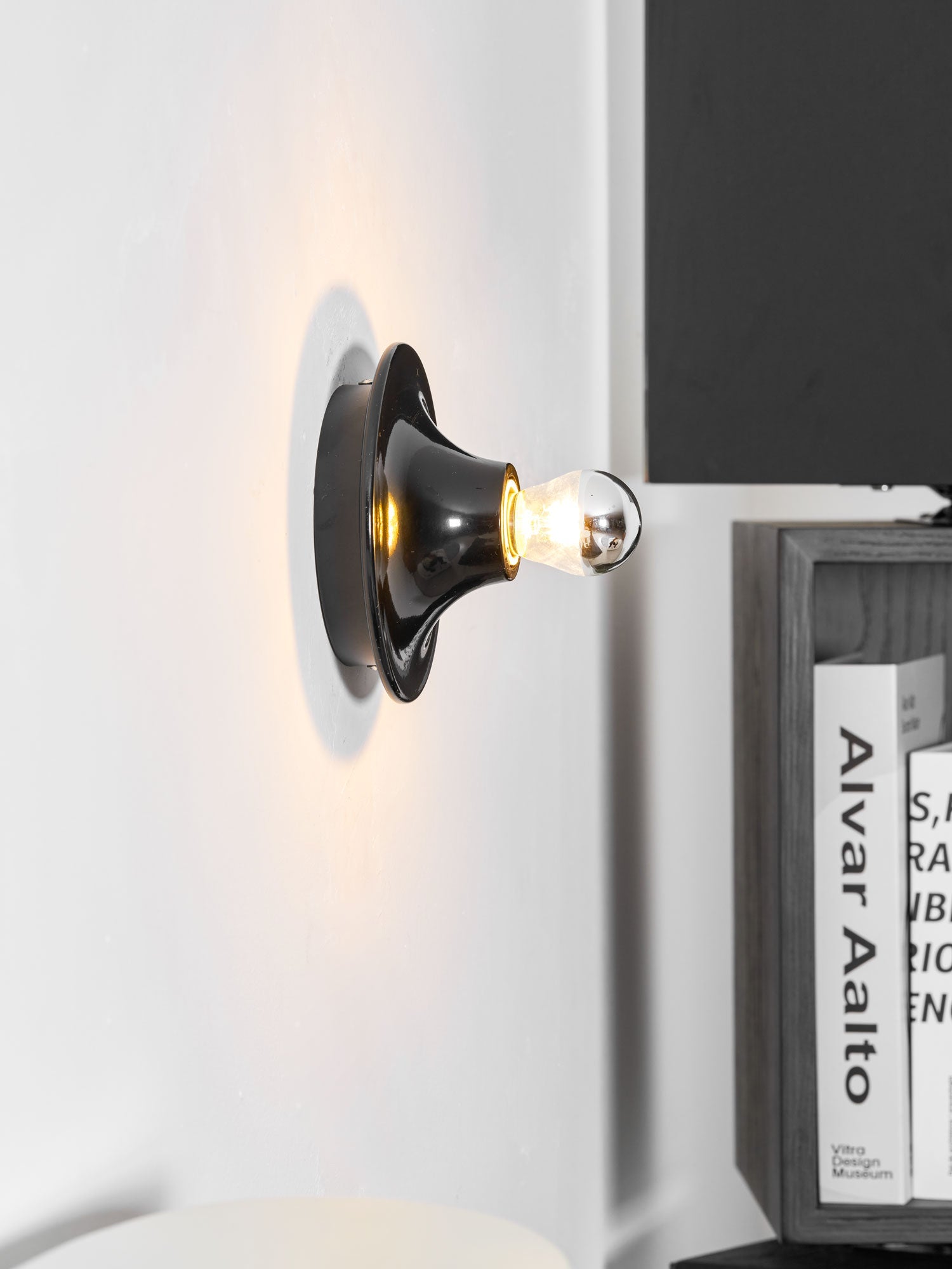 Eclipta wall sconce glowing beside a piece of wall art