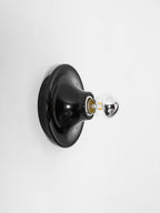 Eclipta wall sconce reflecting warm light from its mirrored bulb