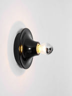 Eclipta wall sconce glowing in a quiet, modern interior