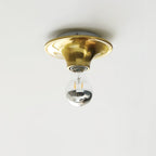 Eclipta wall sconce with a white glass bulb on a neutral wall