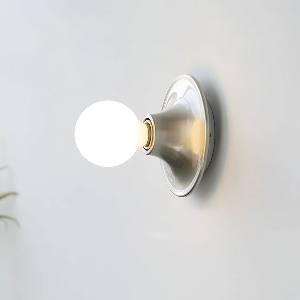 Eclipta wall sconce with a mirrored glass bulb casting a soft halo on the wall
