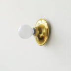 Eclipta wall sconce glowing warmly in a minimalist hallway