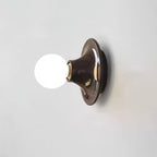 Trumpet-shaped metal base of the Eclipta wall sconce holding a glass bulb