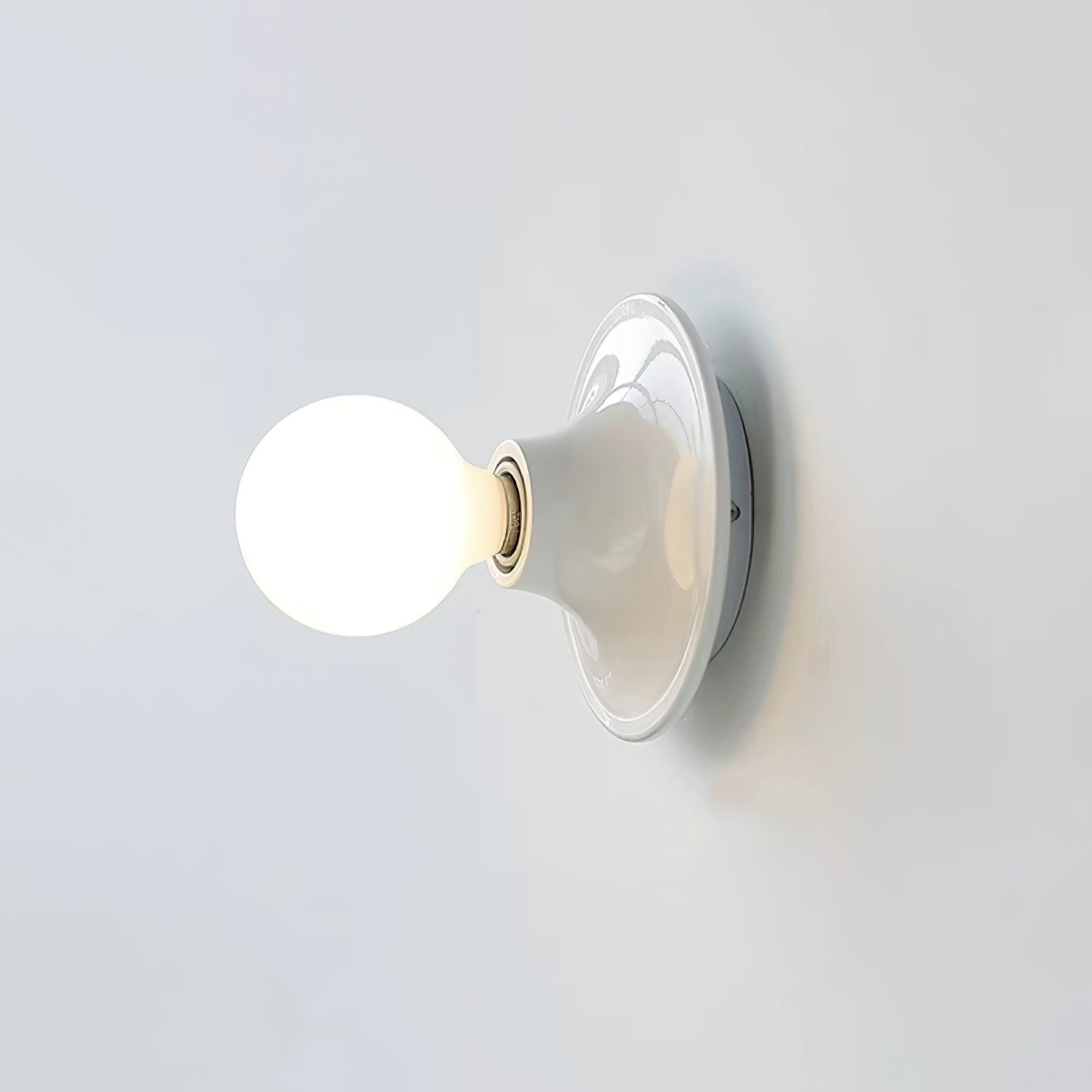 Eclipta wall sconce glowing softly in a minimalist interior