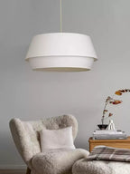 A third view on the grey backdrop shows this Clérachic pendant above the armchair and its wooden side table.