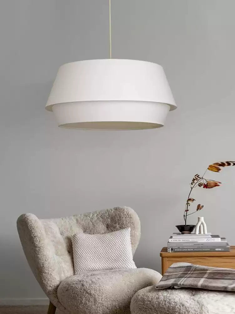 A third view on the grey backdrop shows this Clérachic pendant above the armchair and its wooden side table.