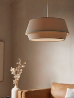 A taupe-toned version of this Clérachic pendant hangs above a rust-orange sofa with a vase of dried stems.