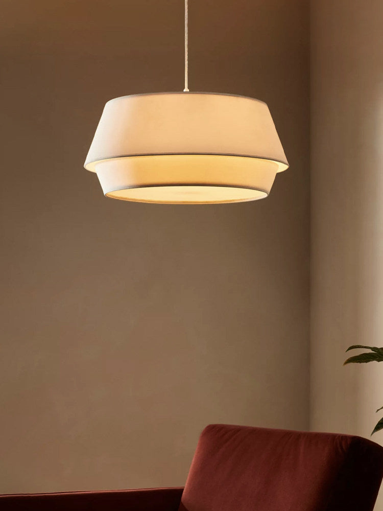 Lit close-up of this Clérachic pendant glowing warmly against a dark, warm-toned wall.
