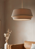 A closer view of this Clérachic pendant in taupe, lit warmly above the rust-orange sofa.
