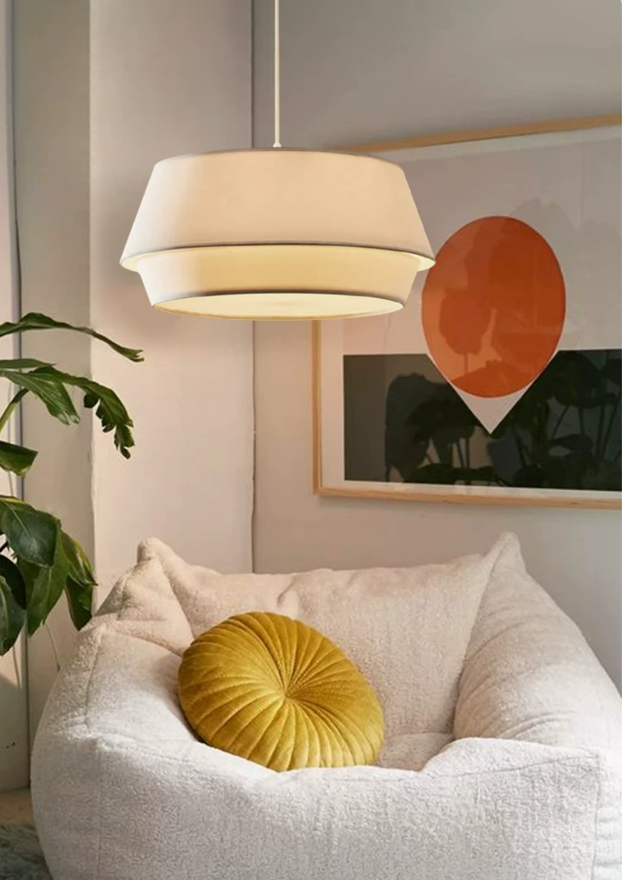 A closer view of the same lit corner, with this Clérachic pendant glowing beside green plant fronds and the mustard cushion.