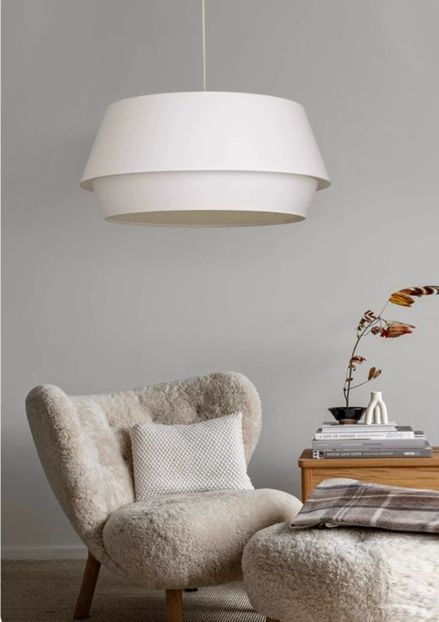 Another angle of this Clérachic pendant above the same bouclé armchair, with dried flowers on the side table.
