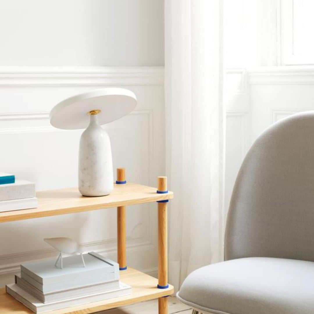 Close crop of the black marble Clérachic table lamp on a white sideboard, framed photo and arch ornament nearby.