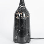 Close-up of the black marble base on the Clérachic table lamp, showing dramatic gold and white veining across the stone.