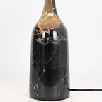 Close-up crop of the black marble base on the Clérachic table lamp, showing its gold-veined surface against white.