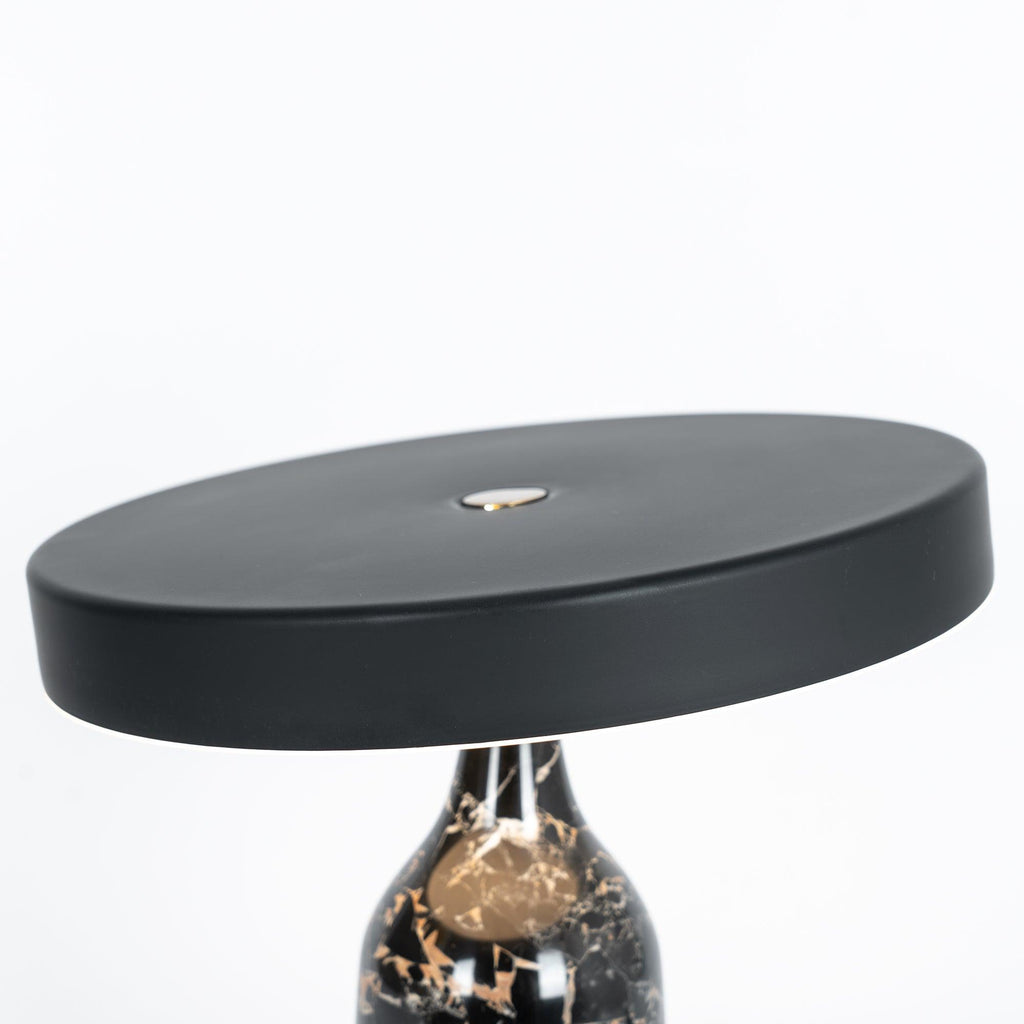 Black marble Clérachic table lamp, disc shade tilted, cropped close to show the top of the veined base beneath it.