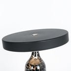Black marble Clérachic table lamp, disc shade tilted, cropped close to show the top of the veined base beneath it.
