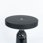 Black marble Clérachic table lamp with its disc shade held level, cropped close to show the gold-veined base below.