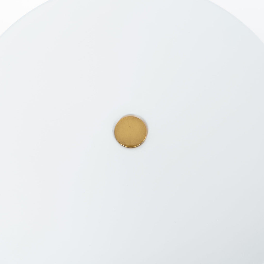 Macro close-up of the brass pivot knob at the centre of the Clérachic table lamp's white disc shade.
