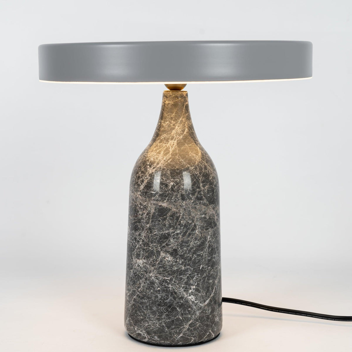 Grey marble Clérachic table lamp with its disc shade tilted to one side, shown with its cord on a white background.