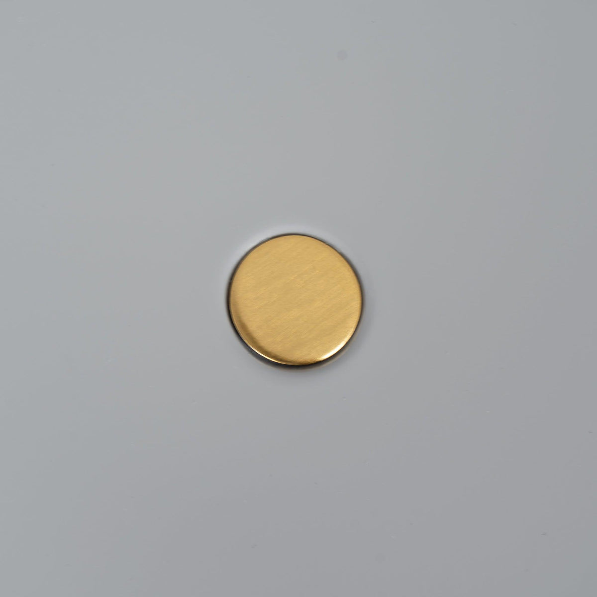 Macro close-up of the brass pivot knob at the centre of the Clérachic table lamp's grey disc shade.