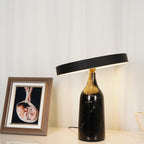 Set closer beside a framed baby photo, this Clérachic lamp's tilted disc shade glows warm above its black marble bottle base.