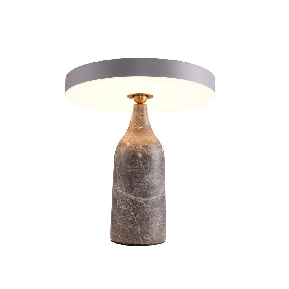 Sitting level on the black marble base, this Clérachic lamp's disc shade glows warm in a ring, its cord visible on white.
