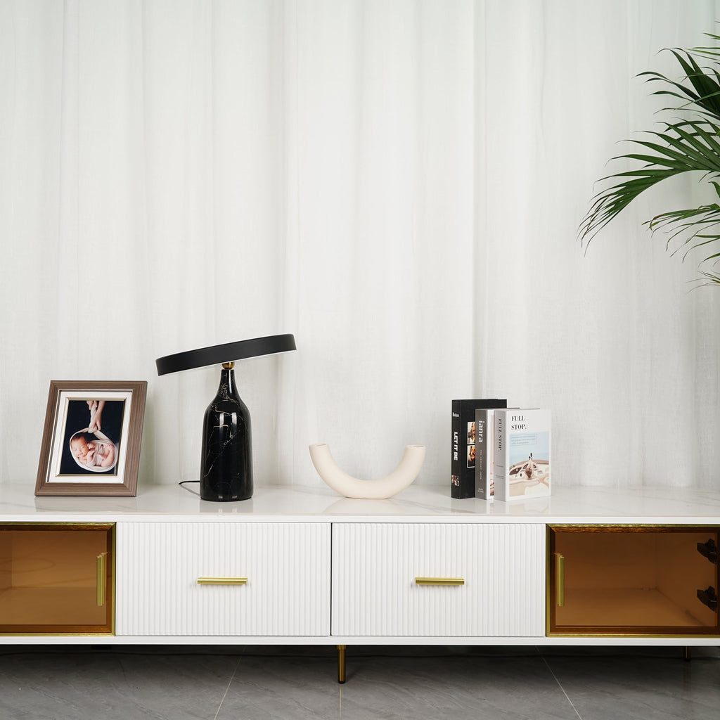 Black marble Clérachic table lamp on a white sideboard beside a framed baby photo, books stacked alongside.