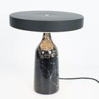 Black marble Clérachic table lamp, disc shade held level, another studio angle with the cord curving to the left.