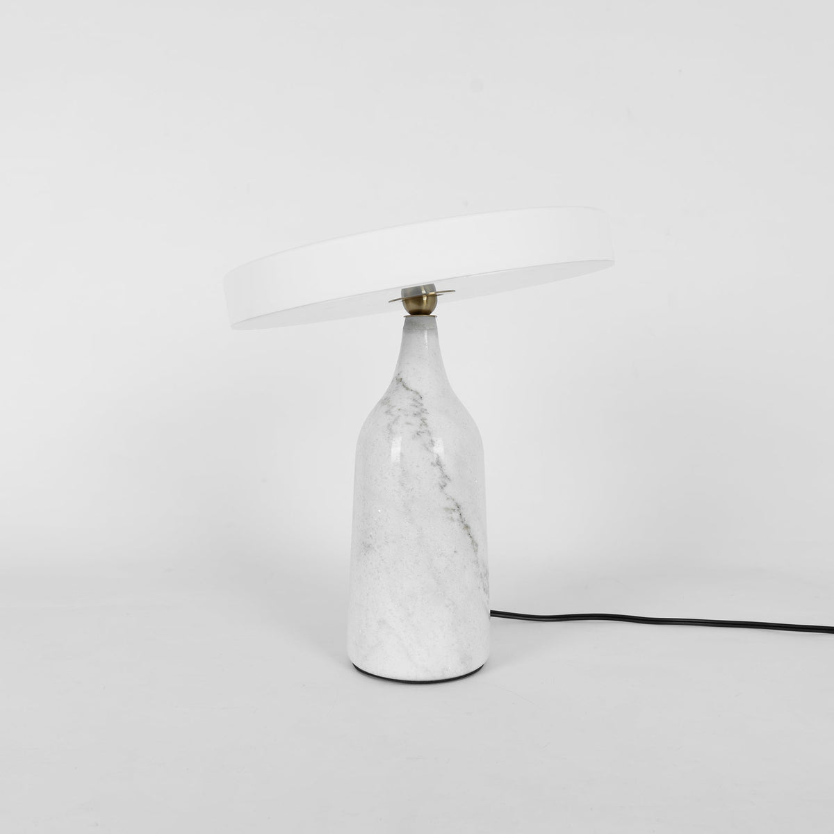 White marble Clérachic table lamp with its disc shade tilted steeply, cropped close with its cord visible.
