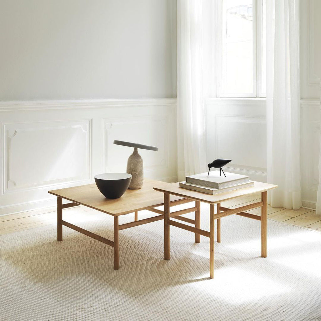 Grey marble Clérachic table lamp on nesting wooden coffee tables beside a small bird figurine and a bowl.