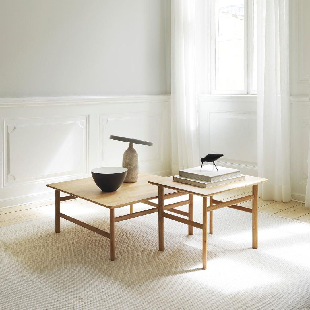 Grey marble Clérachic table lamp on nesting wooden coffee tables beside a small bird figurine and a bowl.