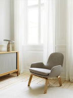 White marble Clérachic table lamp on a wooden console beside a radiator, grey armchair catching the daylight.