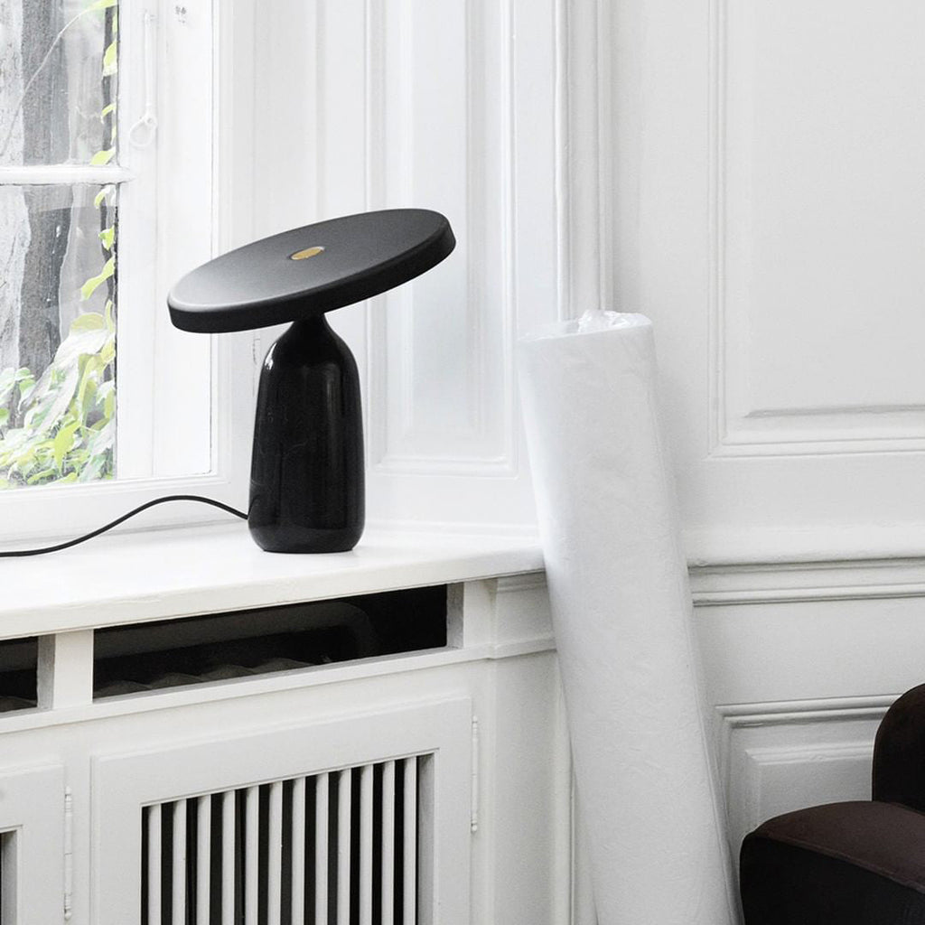 Black Clérachic table lamp on the windowsill, cropped closer to show the disc shade above the rolled white mat.